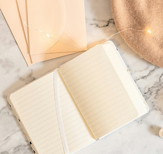 A journal is open on top of a marble table with soft string lights.