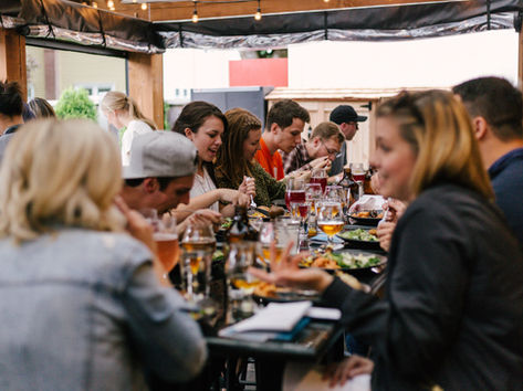 People sitting together at a restaurant table enjoying drinks and food during happy hour.