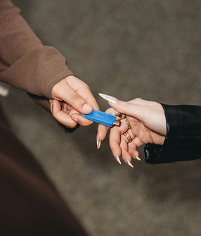 A hand giving a storage unit key to another person's hand.